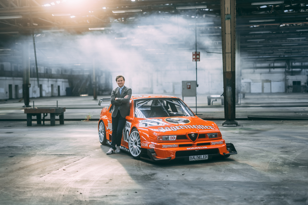 RM Sotheby’s Car Specialist Stephan Knobloch standing with the 1995 Alfa Romeo 155 V6 TI 'Jägermeister' 50th Anniversary